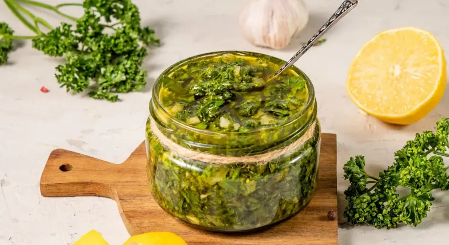 Un vasetto di salmoriglio ricetta, con prezzemolo fresco, limone e aglio, pronto per insaporire i tuoi piatti.