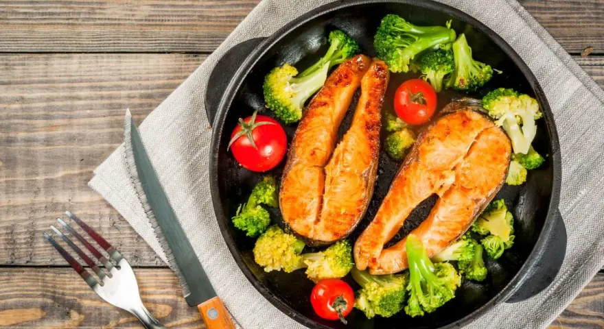 Due tranci di salmone succulento, cotti in padella, accompagnati da broccoli croccanti e pomodorini freschi. Un piatto sano e gustoso.