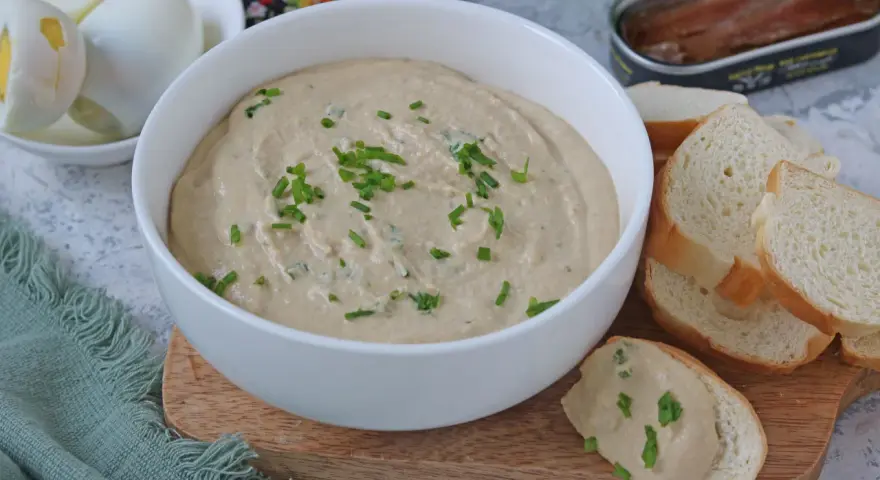Una cremosa salsa tonnata con maionese, guarnita con erba cipollina, pronta per essere gustata con pane tostato e uova sode.