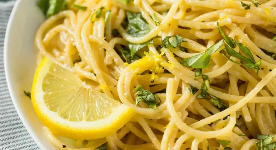 Spaghetti al limone, un classico della ricetta della Costiera Amalfitana, guarniti con scorza di limone e basilico fresco.
