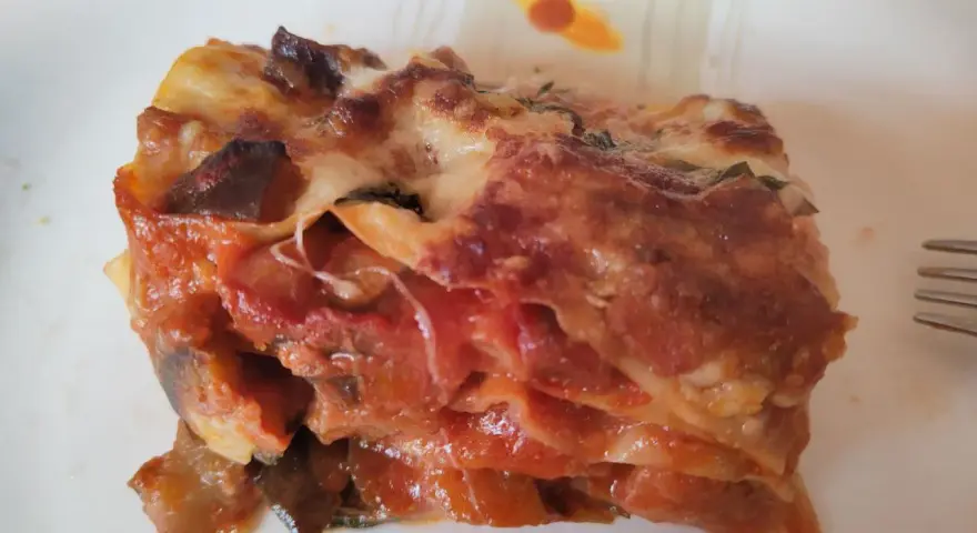 Una fetta di lasagna di melanzane, ricca e saporita, con strati di melanzane, pomodoro e formaggio filante.