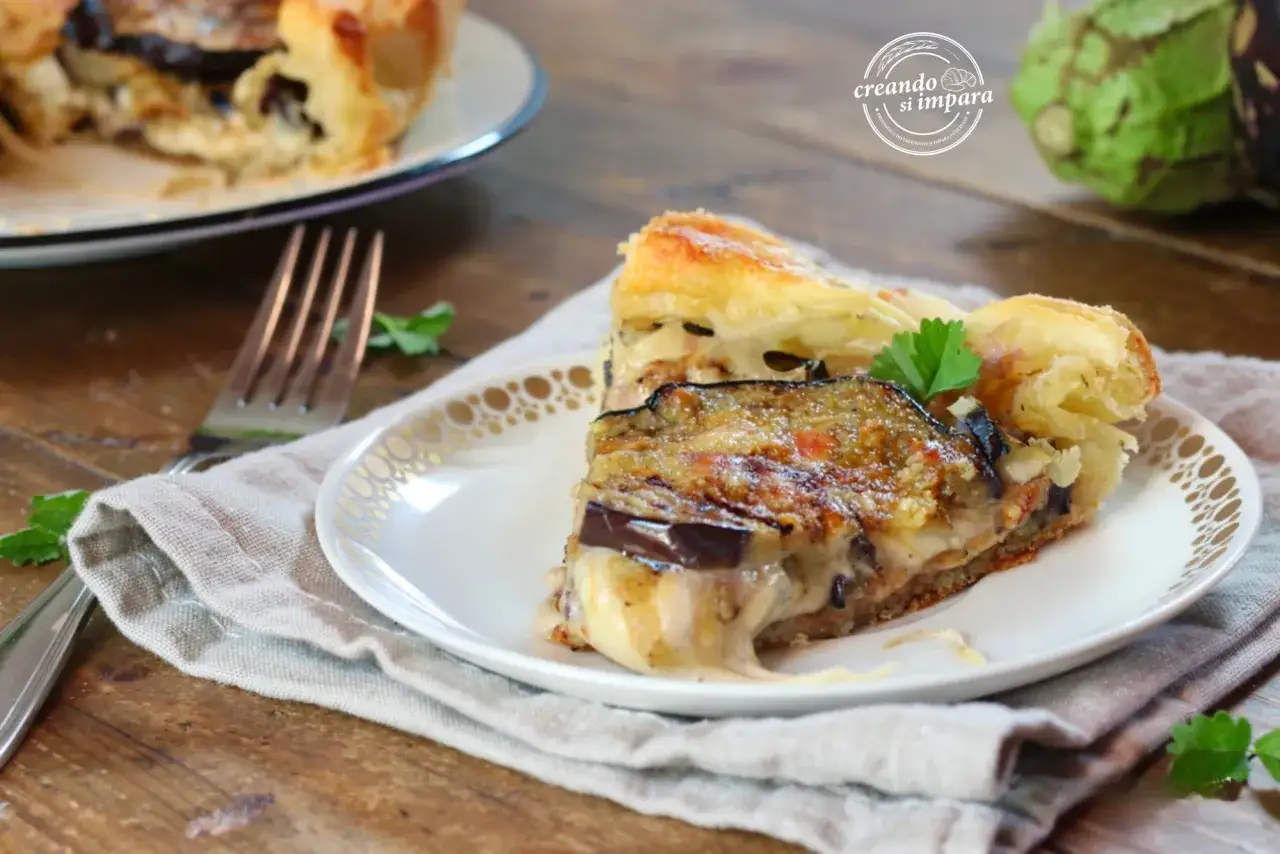Una fetta di torta salata con melanzane, formaggio filante e pasta sfoglia dorata, guarnita con prezzemolo fresco.