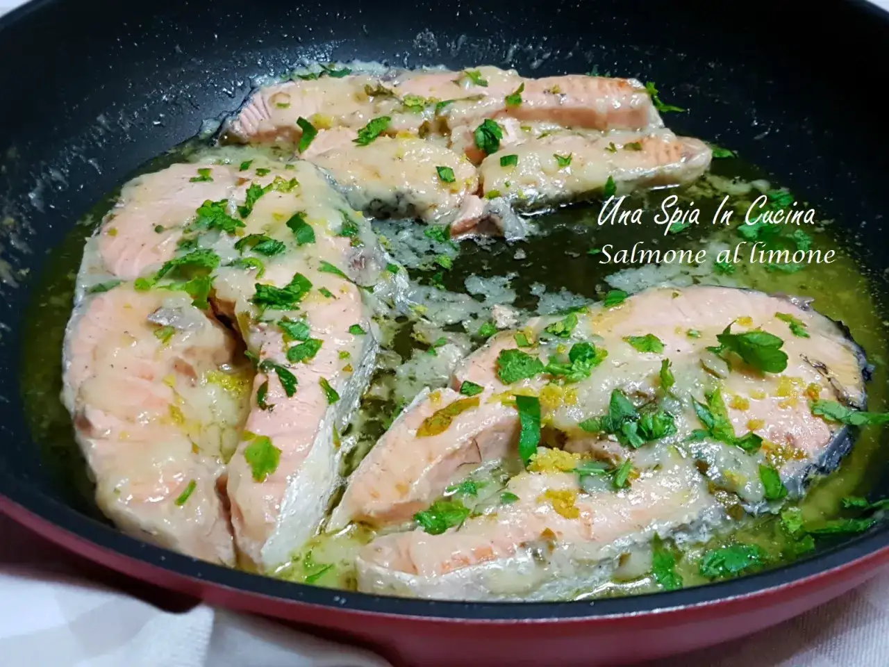 Tranci di salmone in padella, cotti con limone e prezzemolo, emanano un profumo invitante.