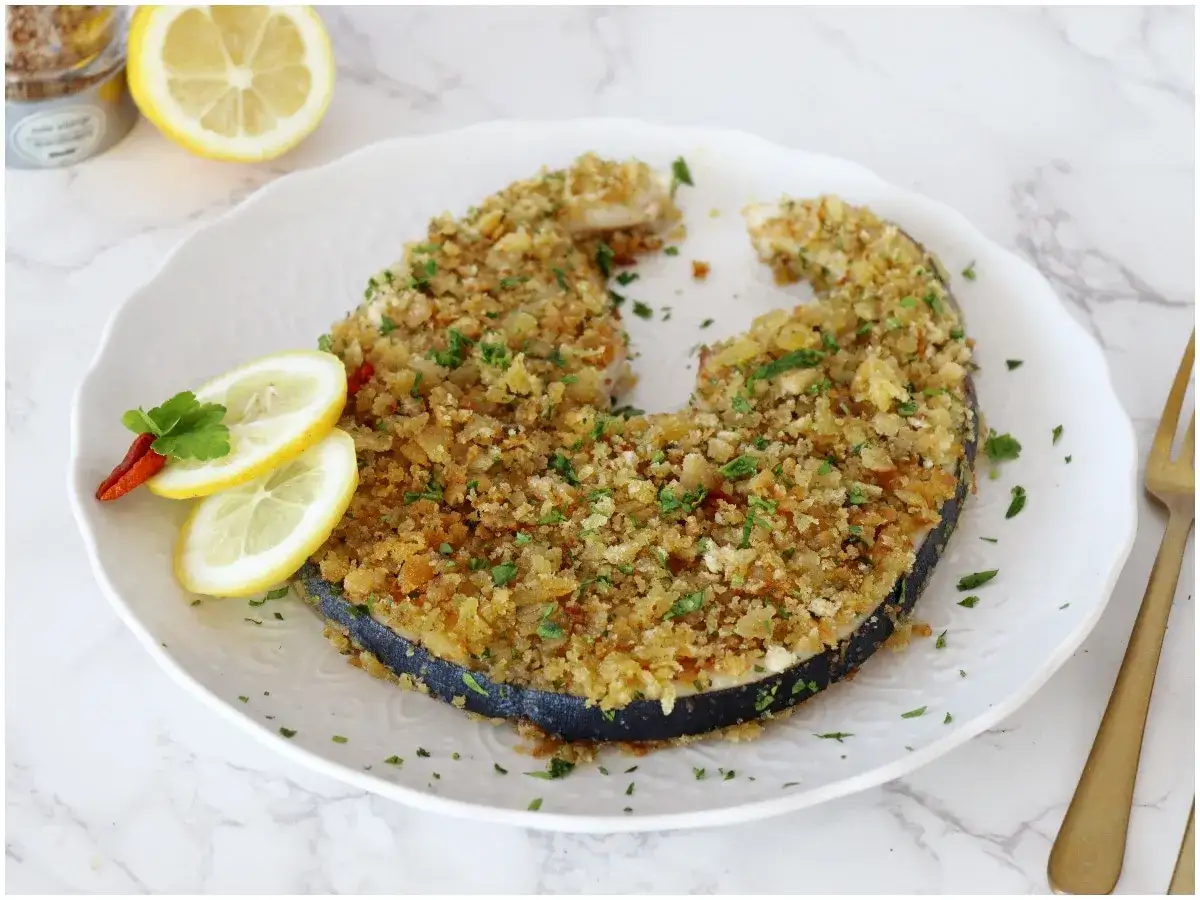 Un succulento pesce spada alla palermitana, cotto al forno con panatura croccante, servito con limone e peperoncino.
