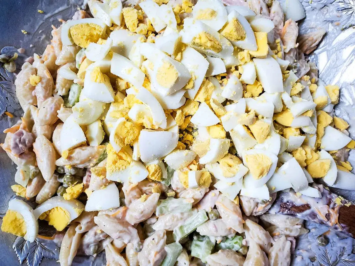 Insalata di pasta cremosa con tonno e abbondanti uova sode a pezzi, un classico piatto estivo.