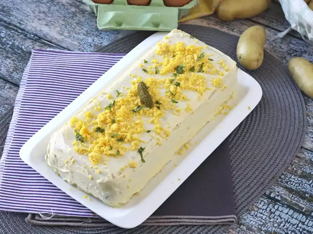 Torta salata con uova sode e maionese, perfetta per una ricetta di pesce finto. Decorata con cetriolini e prezzemolo.
