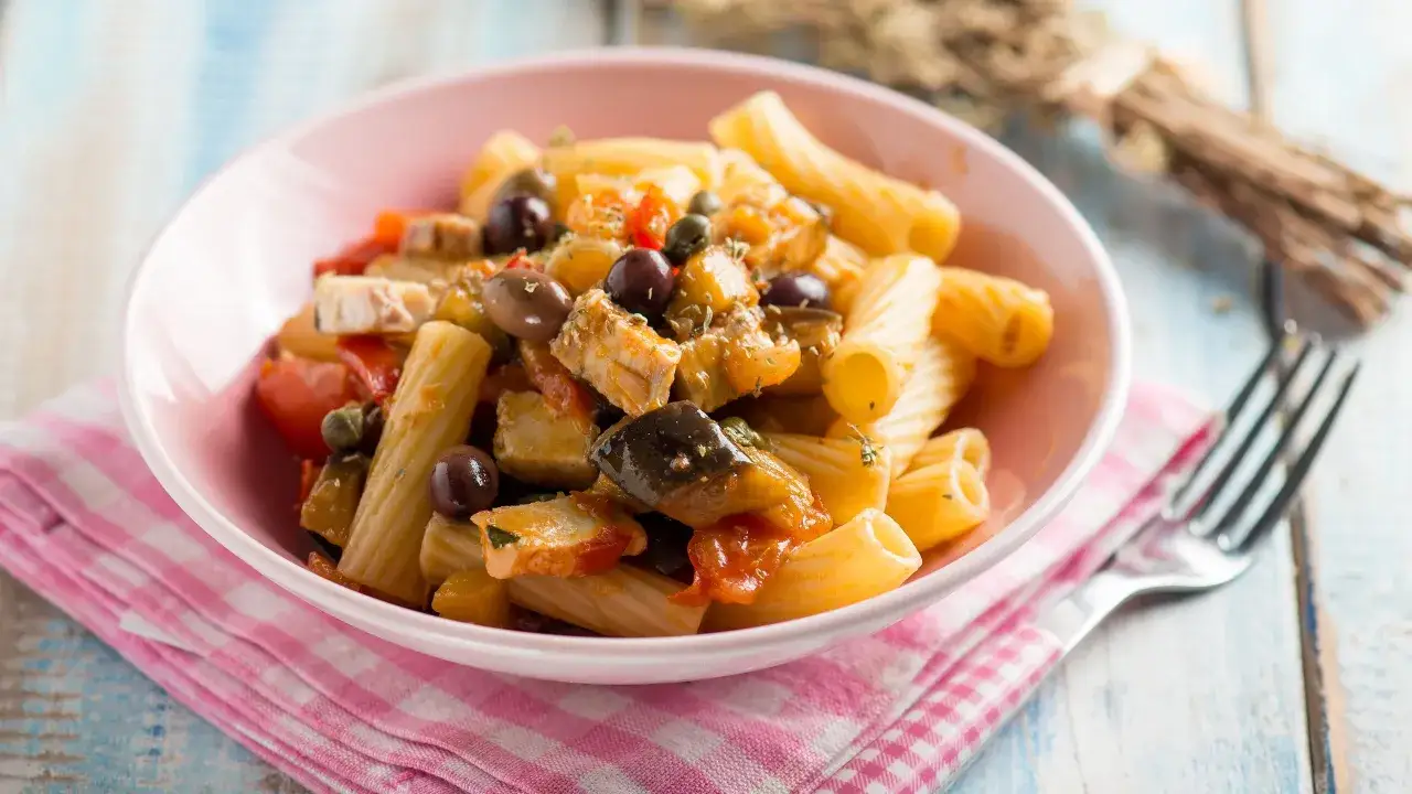 Piatto di pasta con pesce spada, pomodorini, melanzane e olive nere. Un primo piatto gustoso e colorato.