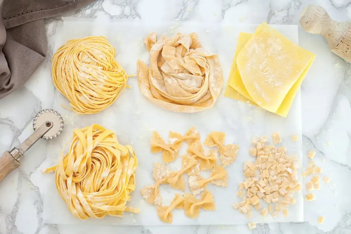 Vari tipi di pasta fresca, tagliatelle, farfalle e quadretti, pronti per una deliziosa pasta fresca ricetta.