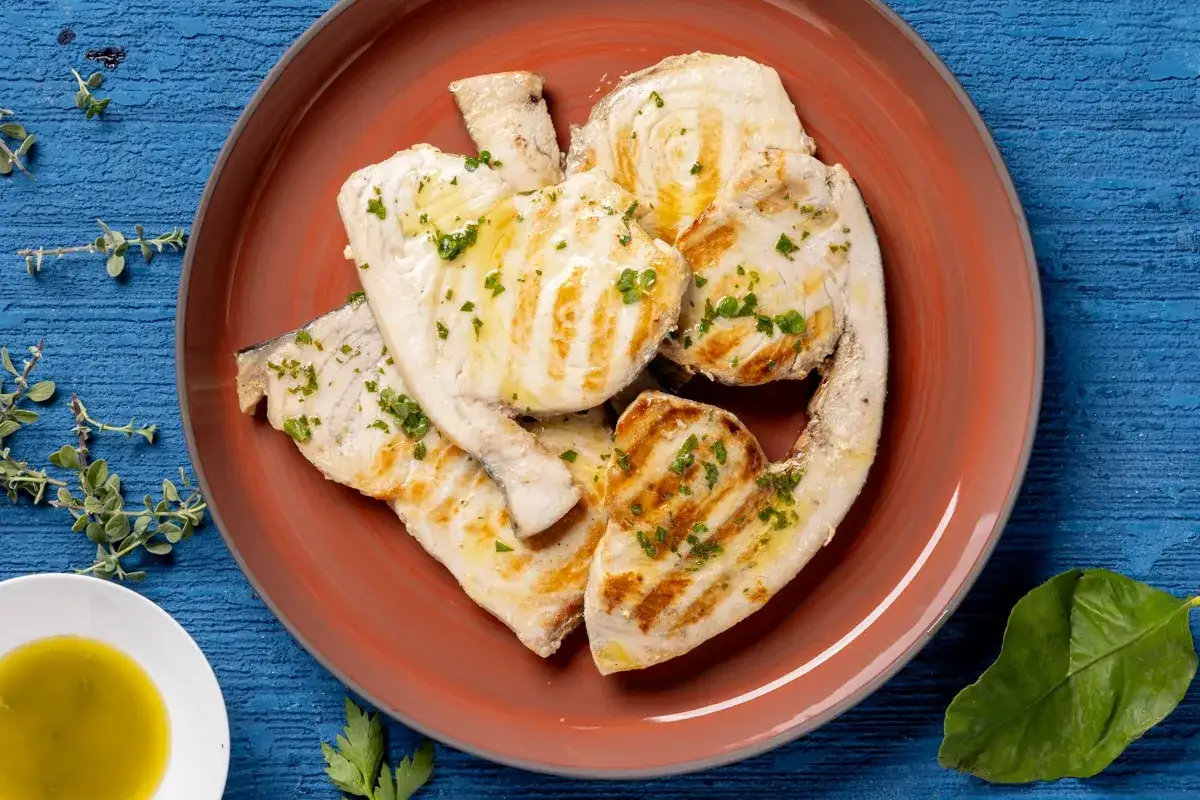 Pesce spada alla griglia, condito con erbe aromatiche e olio, pronto per essere gustato con la salmoriglio ricetta.