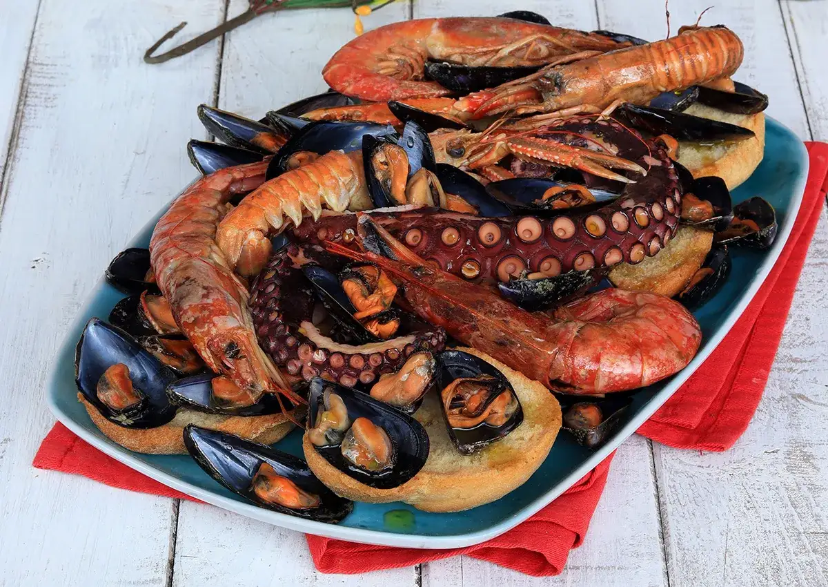Un invitante piatto di zuppa di cozze, gamberi e polpo su pane abbrustolito, pronto per essere gustato.