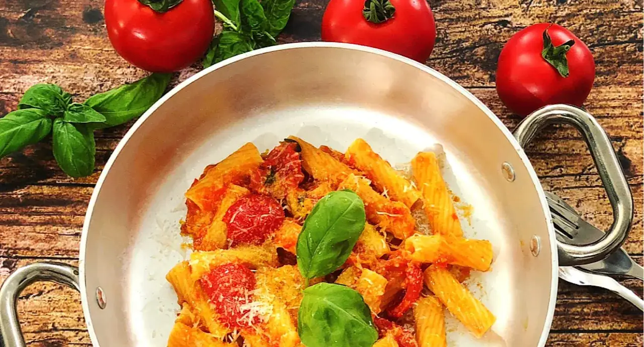 Piatto di pasta scarpariello con pomodorini e basilico fresco, pronto per essere gustato. La scarpariello ricetta &egrave; un classico.
