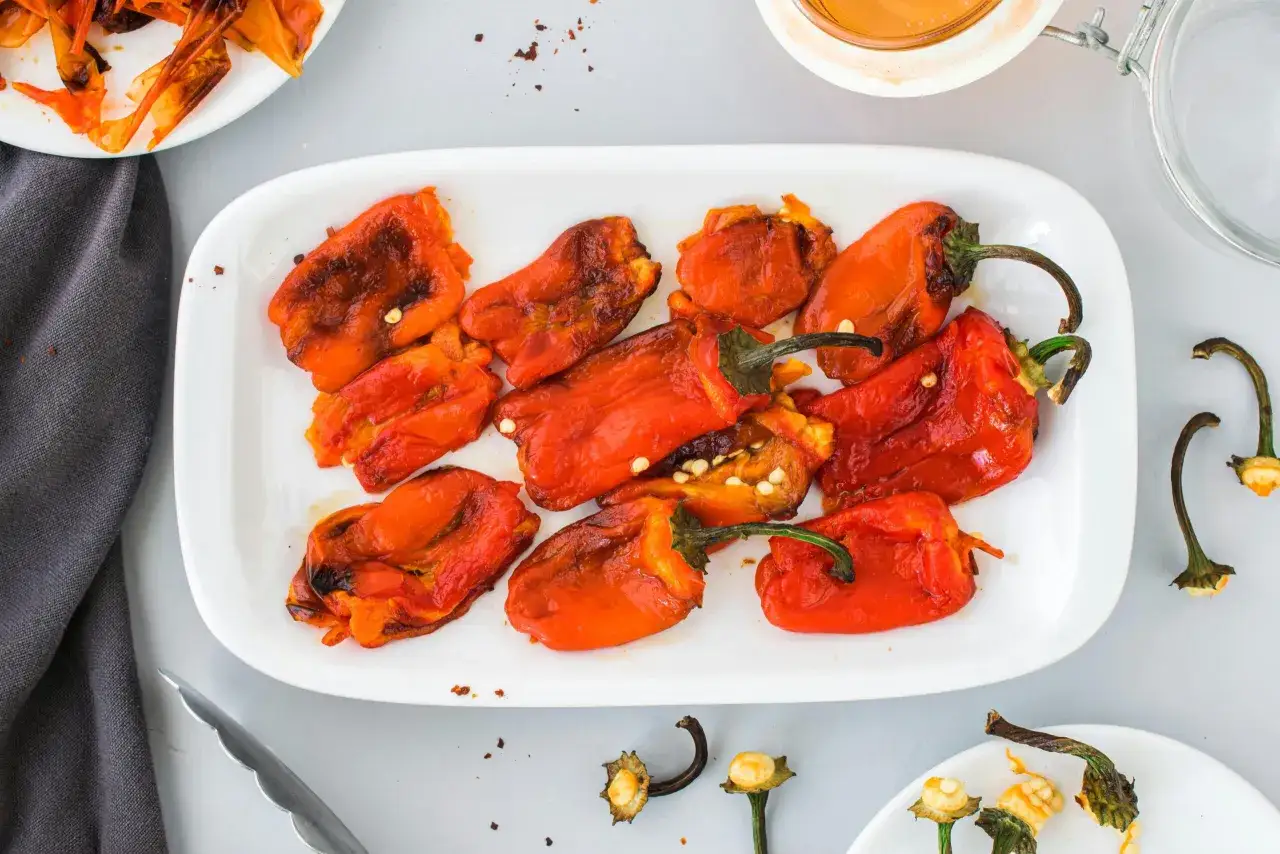 Piatto bianco con peperoni arrostiti, pronti per essere mescolati con la pasta.