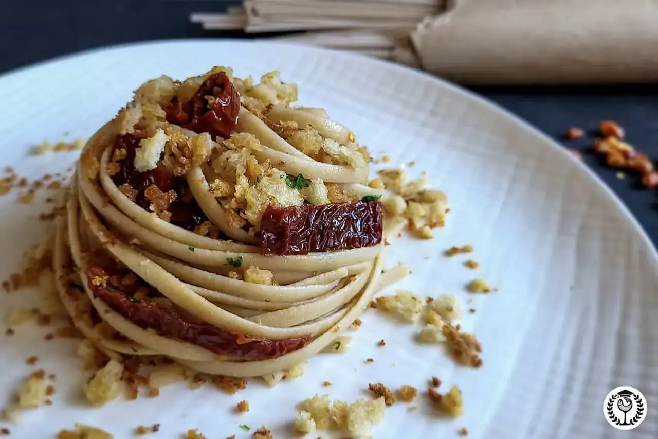 Un nido di pasta con pomodori secchi e pangrattato croccante, un assaggio di stroncatura calabrese che invita al gusto.