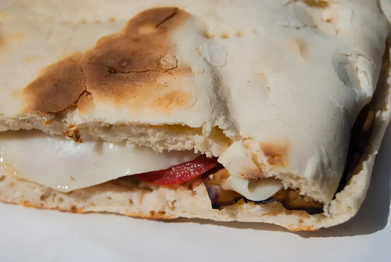 Torta al testo ripiena di formaggio filante, pomodoro e melanzane grigliate. Un morso di gusto!