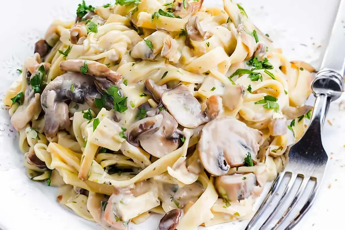 Un piatto invitante di pasta panna e funghi, condita con prezzemolo fresco.