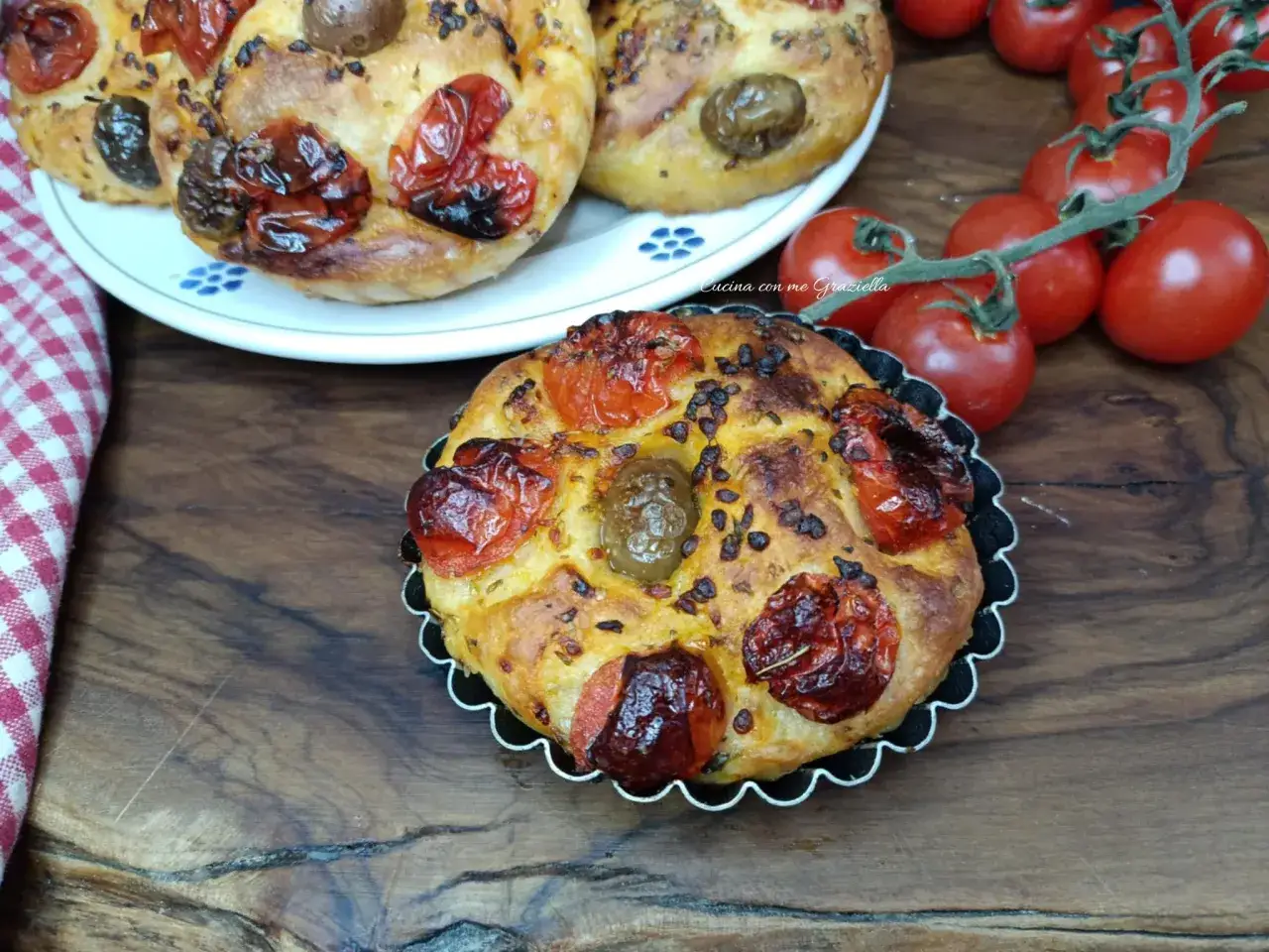 Focaccine pugliesi dorate con pomodorini confit e olive, pronte per essere gustate.