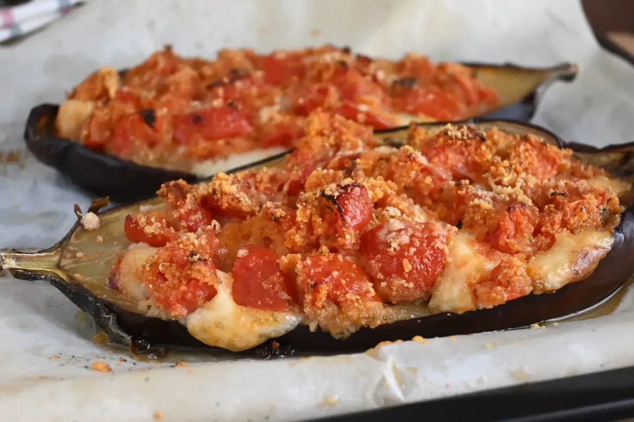 Melanzane ripiene al forno, un delizioso pasticcio di melanzane con pomodoro e formaggio filante, pronte per essere gustate.