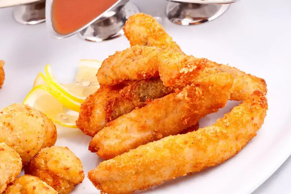 Bastoncini dorati di zucca fritta impanata, croccanti e invitanti, serviti con spicchi di limone e salse.