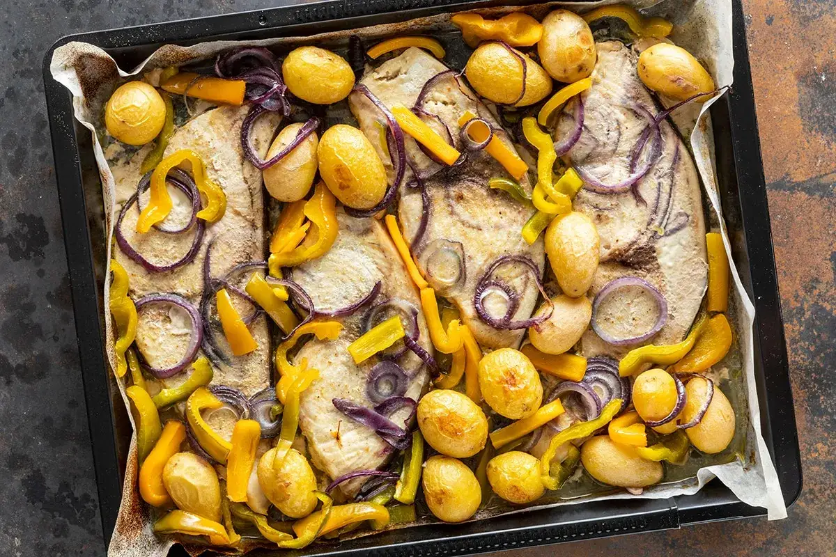 Deliziosi secondi di pesce al forno con patate novelle, peperoni gialli e cipolla rossa.