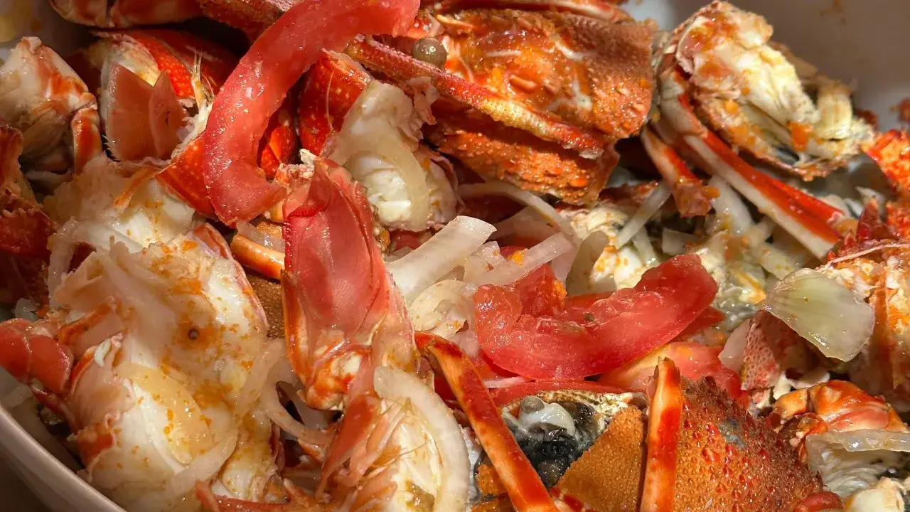 Aragosta alla catalana, un piatto succulento con pezzi di aragosta, pomodoro e cipolla, pronto per essere gustato.