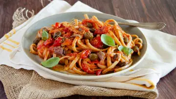 Pasta con sugo rosso, olive, acciughe e basilico, un assaggio di **stroncatura calabrese**.