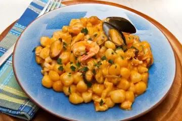 Gnocchi di patate con frutti di mare, gamberi e cozze, guarniti con prezzemolo fresco.